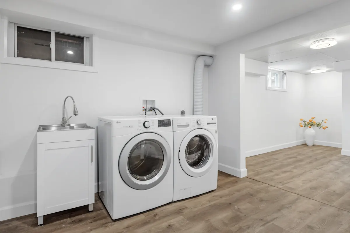 Basement laundry area with a sink and two appliances
