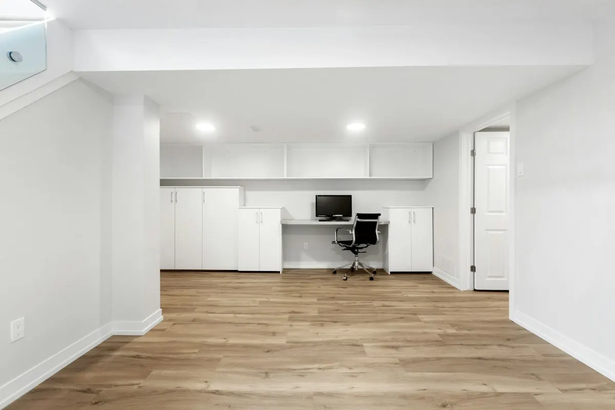 Basement workspace with a small desk and white cupboards