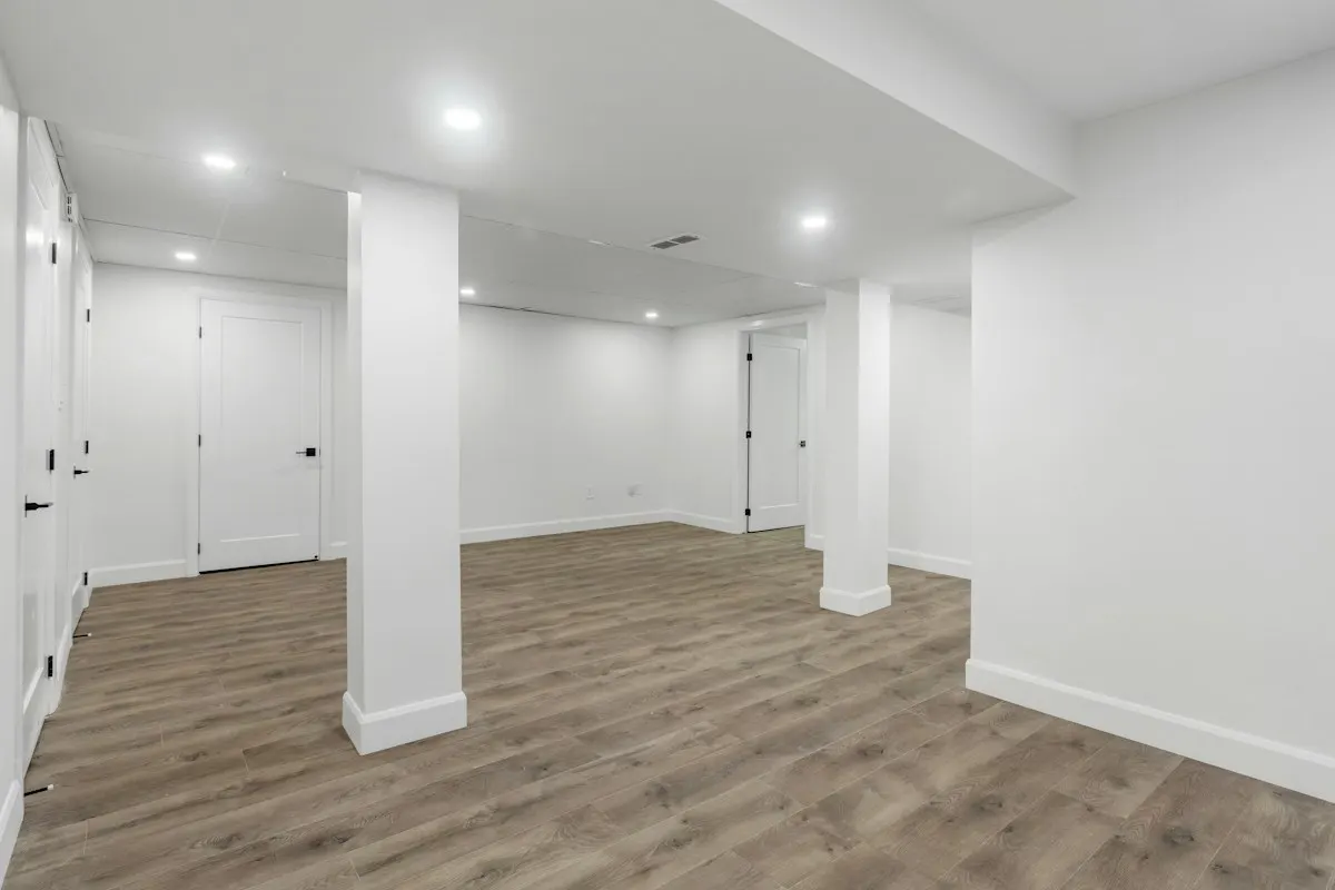 Finished basement room with timber-look flooring and columns